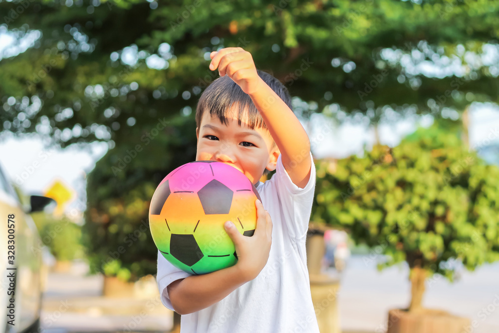 Portrait image of 5-6 boy. Happy Asian child boy playing and holding a football toy in his hands. He wear white shirt at the field playground. Happy and smiling boy. Sport and kid concept. Portrait image of 5-6 boy. Happy Asian child boy playing and holding a football toy in his hands. He wear white shirt at the field playground. Happy and smiling boy. Sport and kid concept.