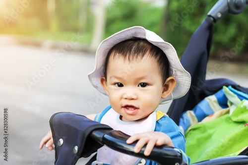 Portrait image of 1-2 baby. Happy Asian child girl smiling and laughing. She sitting in a stroller at the garden park. Relaxing and Emotion of kid concept.