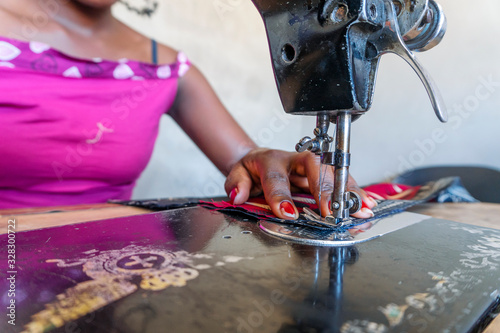 Seamstress using her black sewing machine to do African dresses