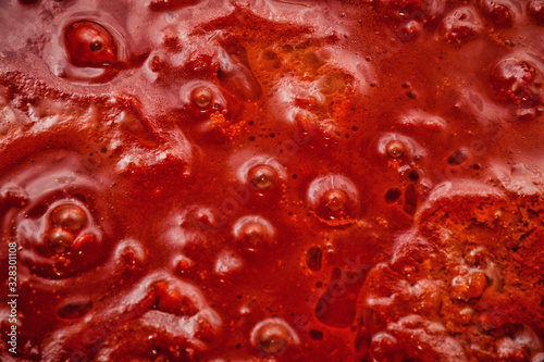 Closeup macro photo of rich red tomato vegetable sauce boiling in saucepan in the process of cooking tasty appetizer for pizza or pasta