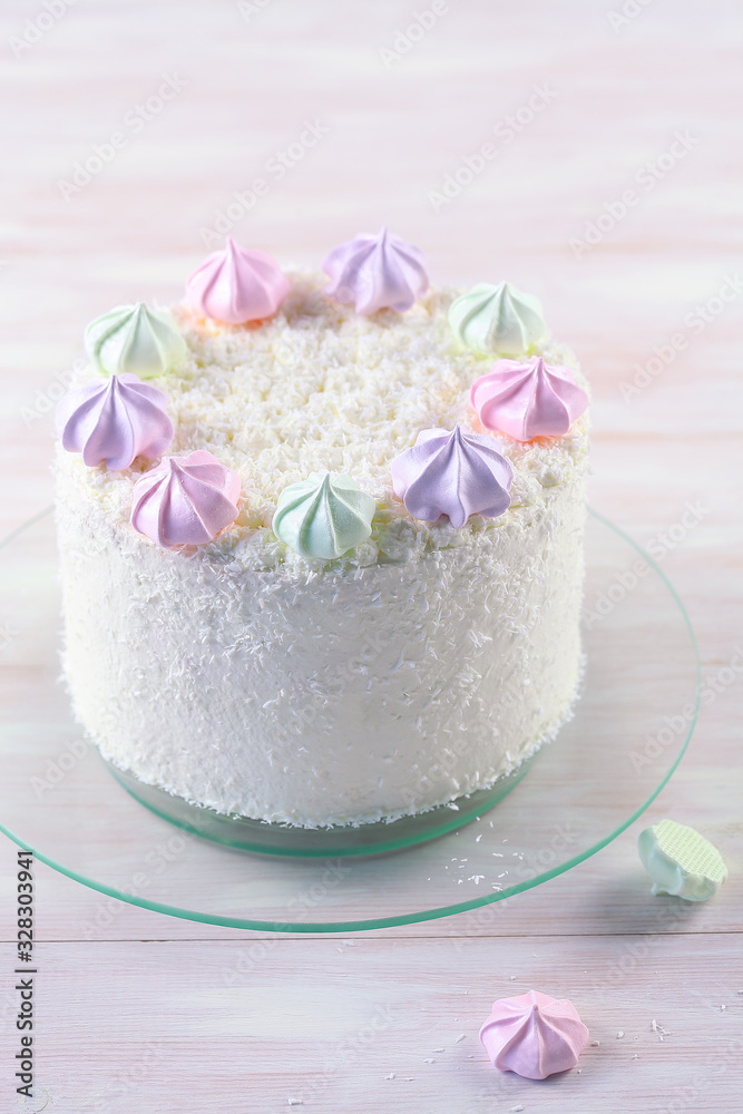 Cherry Layer Cake decorated with fine coconut flakes and colored meringue cookies, on white wooden background. Cherry Layer Cake decorated with fine coconut flakes and colored meringue cookies, on white wooden background.