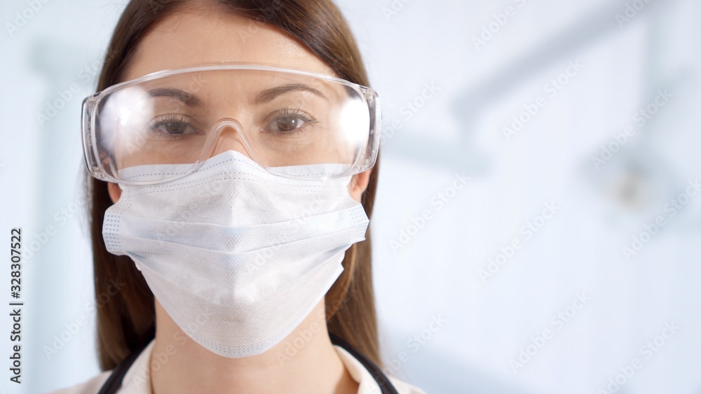 Portrait of professional female doctor in mask standing in hospital room. Woman physician at work Portrait of professional female doctor in mask standing in hospital room. Woman physician at work