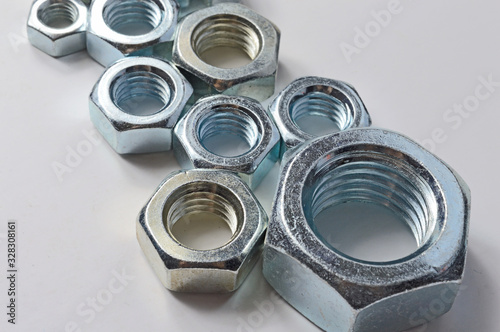 New chrome screw-nut of different sizes on a white background. Concept.