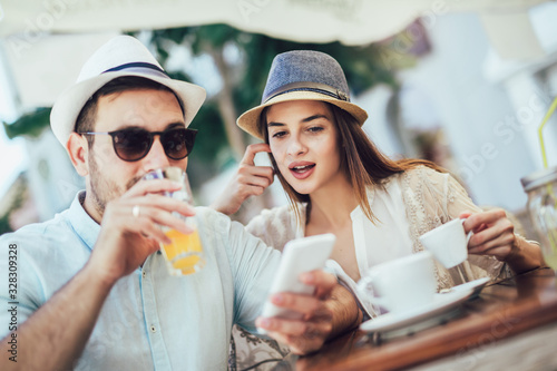 Beautiful loving couple sitting in a cafe enjoying in coffee and using phone