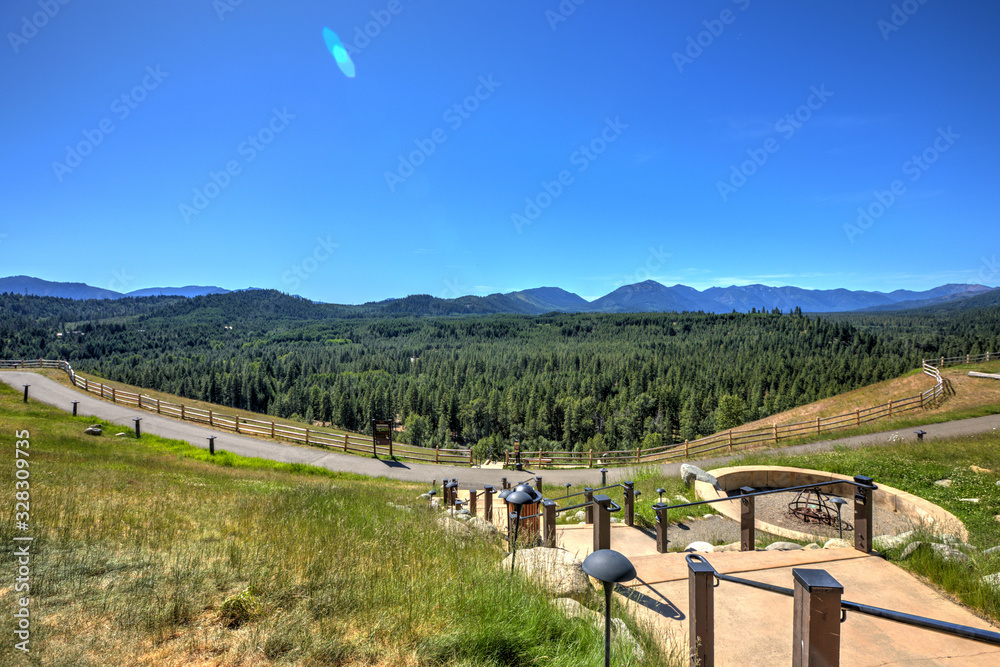 Beautiful open valley with Cascade mountains and pine trees and large lodge with deck.