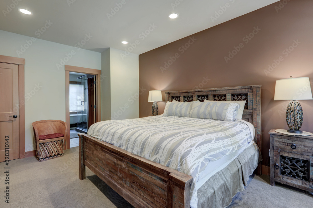 Luxury bedroom with huge bed and great furniture. Rustic heavy wood with metal elements and brown wall.