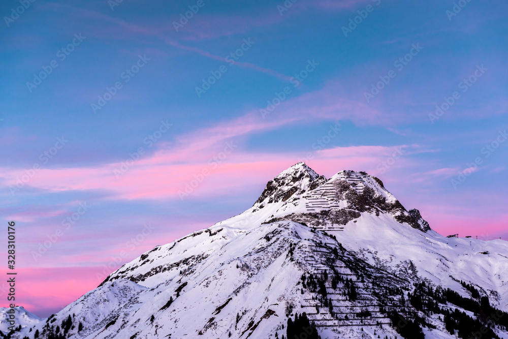 Pink clouds lie in a blue sky above a snowy alpine mountain peak. Stock ...