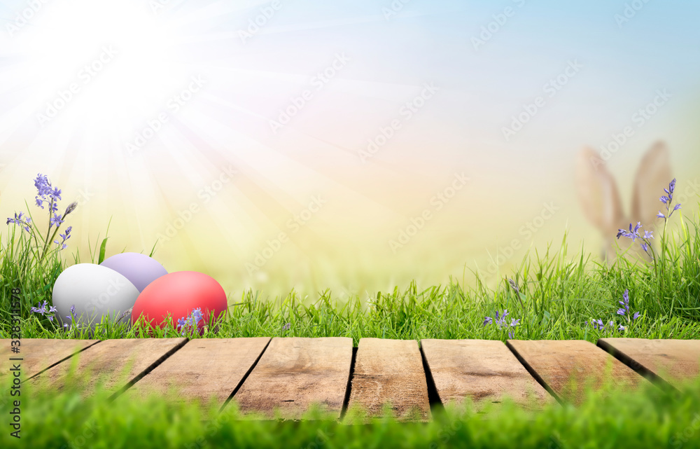 A wooden product display top with an Easter background of painted eggs,  rabbit ears, green grass and meadows. Stock Photo | Adobe Stock