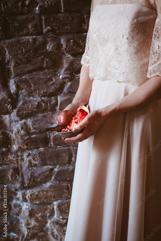 The girl in the wedding dress holds a pomegranate in the palms
