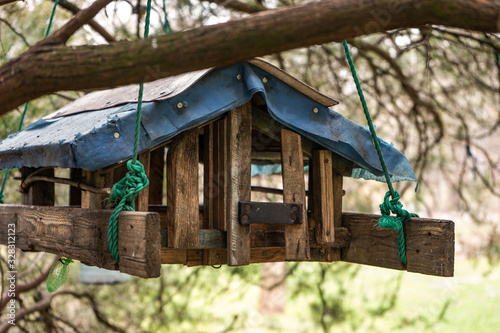 homemade wooden bird feeder and squirrels in the form of a house hanging on a tree. winter care for animals and birds