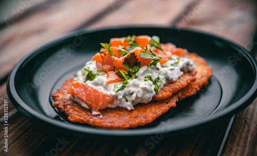 potato pancakes with salmon fish and sour cream in a plate on wooden table