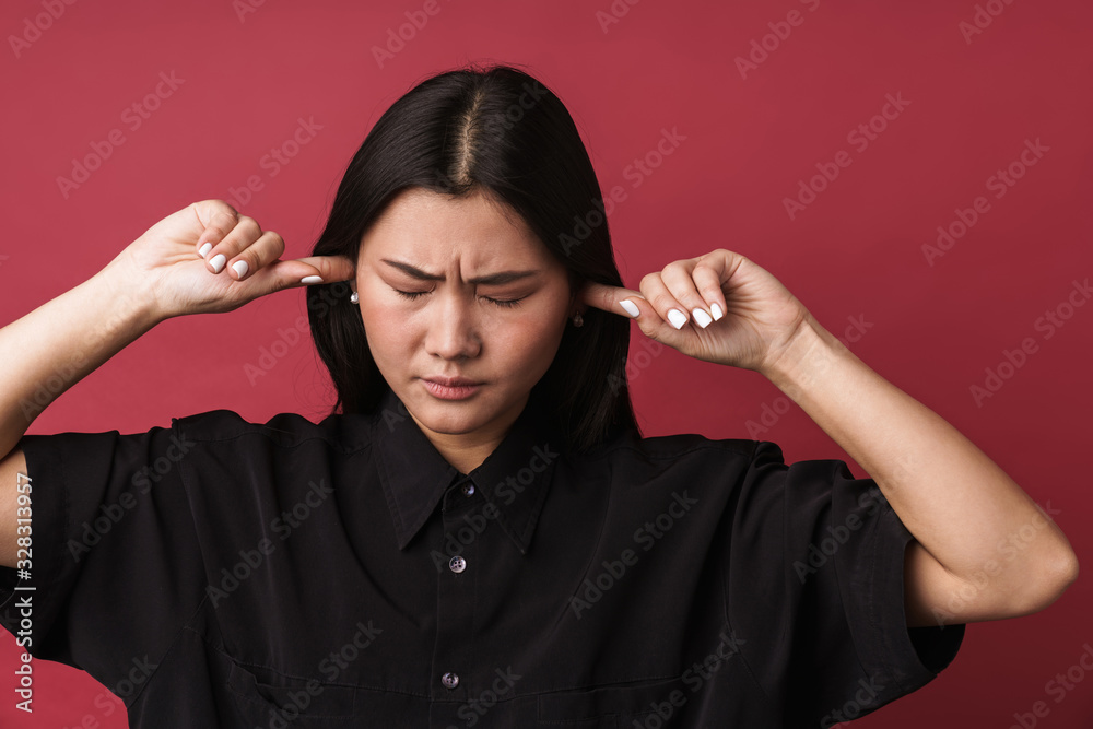Obraz premium Displeased asian young woman covering ears
