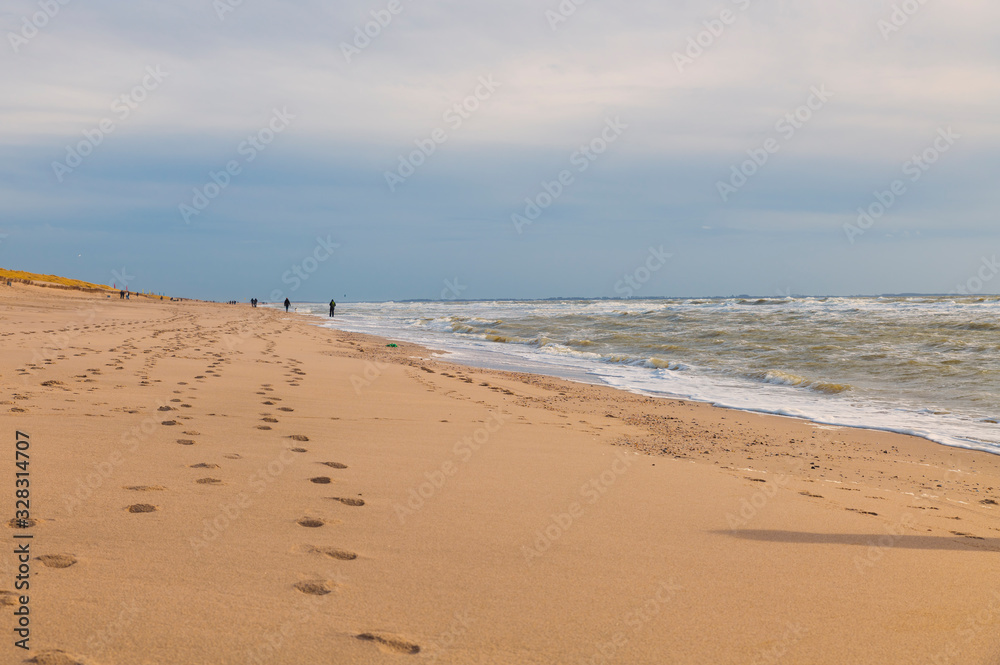 people walking at the beach during hard wind