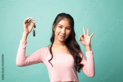 Cute asian girl showing car key.