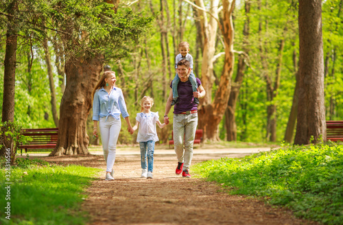 Happy young family parents with child in green summer city park have fun walking together