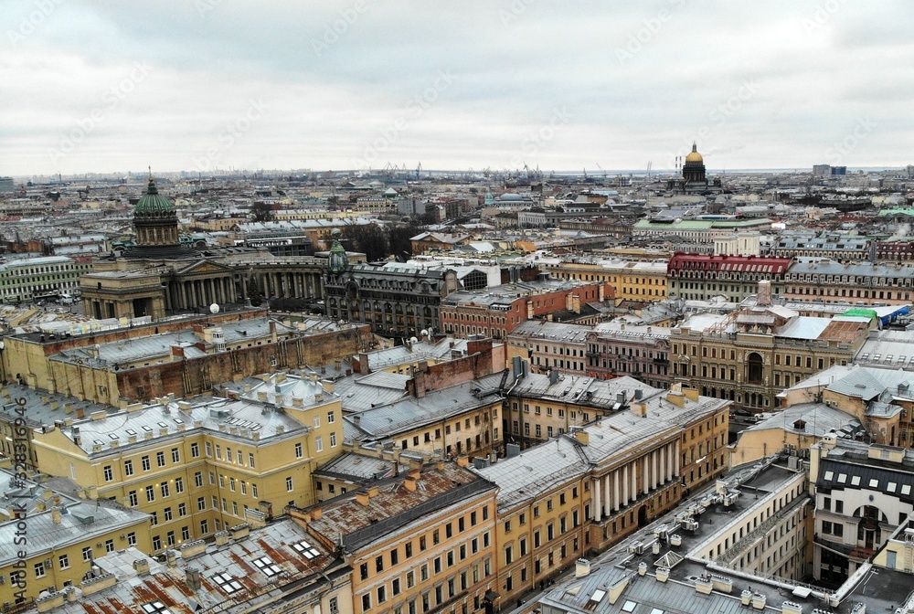 Aerial view of Griboyedov Canal and Kazan Cathedral and Saint Isaac's Cathedral with high traffic at winter. different roofs of citycenter of Saint-Petersburg cityscape. Sea port cranes on backstage