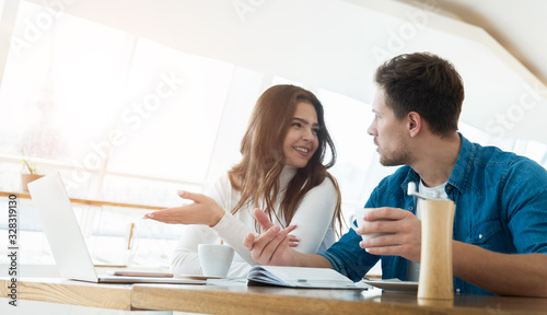 two young colleagues brunette woman and handsome man working in laptop during lunch break at cafe, teamwork and multitasking concept photo