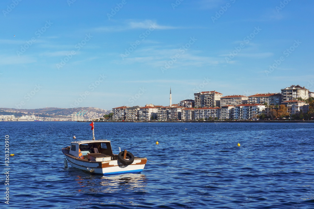 Picturesque panoramic view of Degirmendere (Kocaeli, Turkey) at sunny winter day. Bright blue water and small fishing boat in the foreground