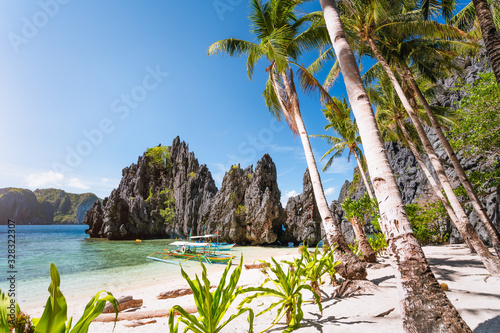 Hidden beach with first tourist trip boats in morning sun light at El Nido, Palawan, Philippines