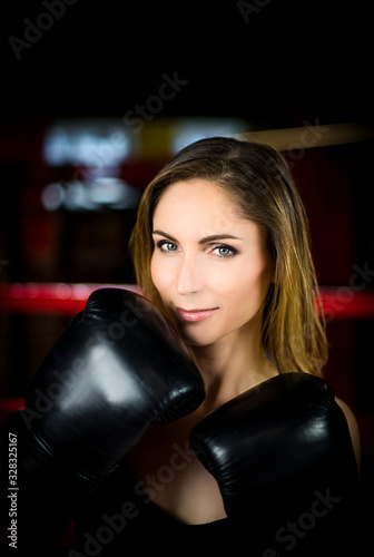 Girl and Boxing. Large portrait of a beautiful girl in black Boxing gloves in a red ring. Vertical photography
