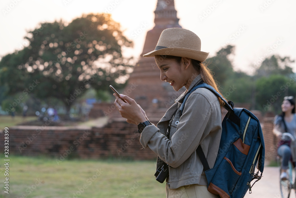 An Asian young woman checking on mobile phone while traveling in the ancient city.