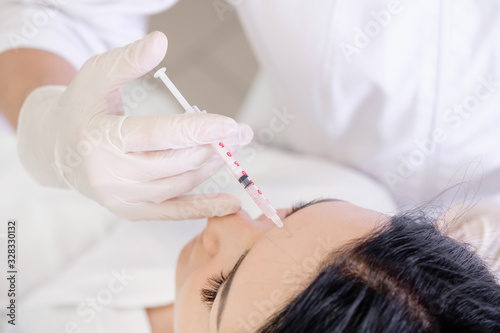 Beauty procedure. Portrait young woman receiving hyaluronic acid injection in a forehead. Painful procedure on female face. Lifting skin treatment
