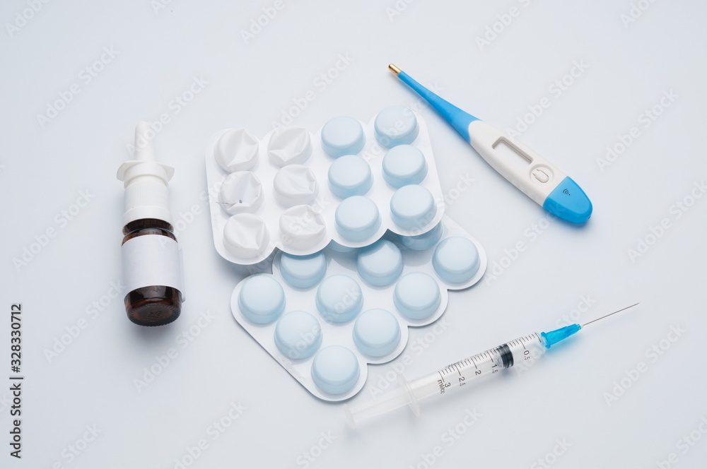 Nasal spray, syringe, tablets and thermometer on blue background Nasal spray, syringe, tablets and thermometer on blue background