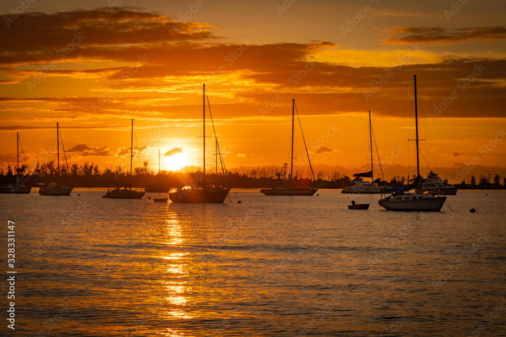 sailboats anchored together silhouette with sunset in background