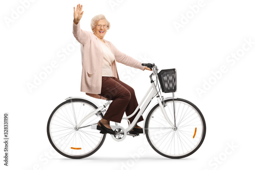 Senior woman riding a bicycle and waving at camera
