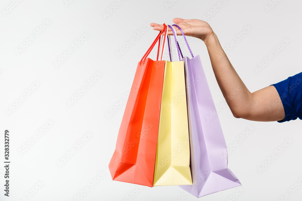 Cropped image of female shopper carrying colorful paper shopping bags