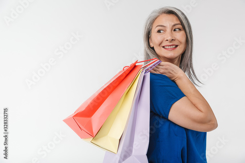 Image of adult woman with long gray hair carrying paper shopping bags