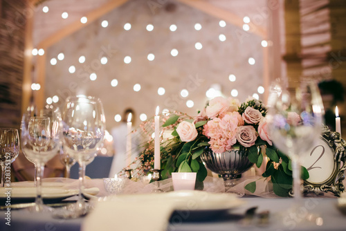festive wedding table with lights, flowers, dishes and glasses