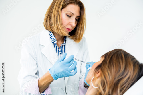 Beautician holding syringe near female facial skin doing injections. Woman getting hyaluronic injection.