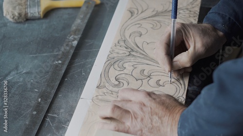 Worker traces lines on the fluted paper using a pen and a carbon paper, translates the picture to a stone