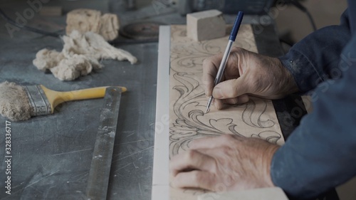 Engraver artist lines the lines on the fluted paper using a pen and a carbon paper, translates the drawing onto a stone blank