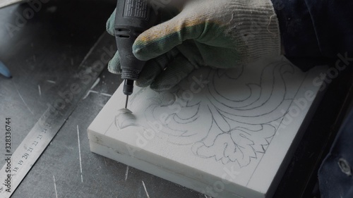 Engineer engraver working with tools on a marble ornament plate, close up