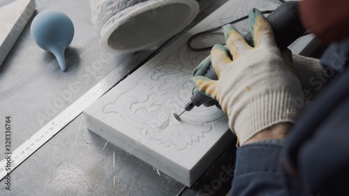 The artist's hands cut out a piece of marble slab, pattern applied manually