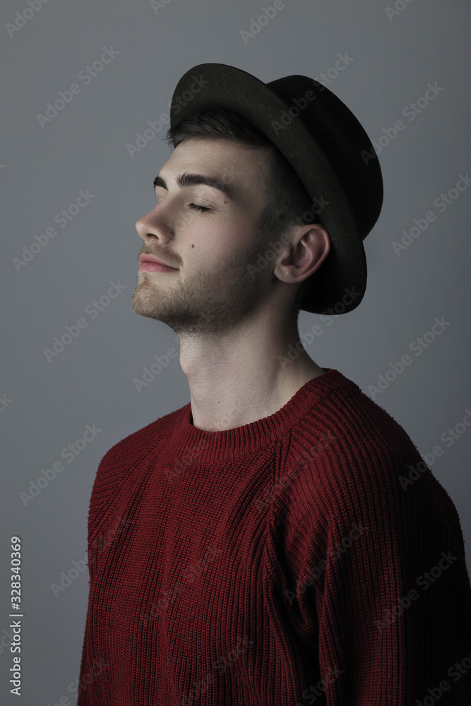 Portrait of a young man with closed eyes standing against grey background Portrait of a young man with closed eyes standing against grey background