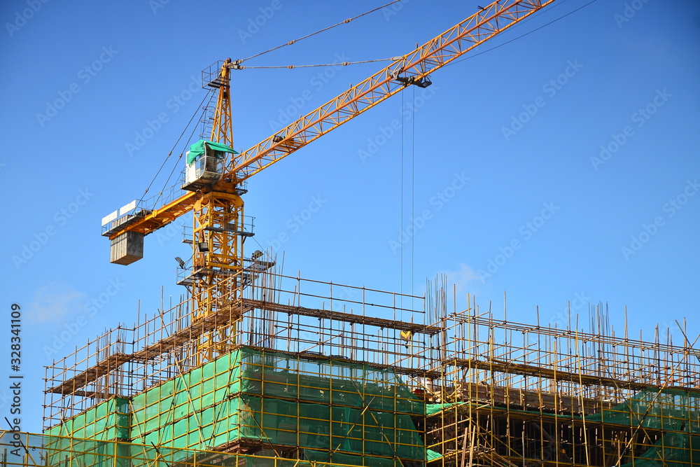 Large tower crane on construction site with blue sky and white clouds