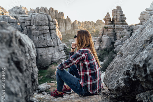 Young woman explorer sitting, looking at the mountains. Concept of adventure, excursion and trips.