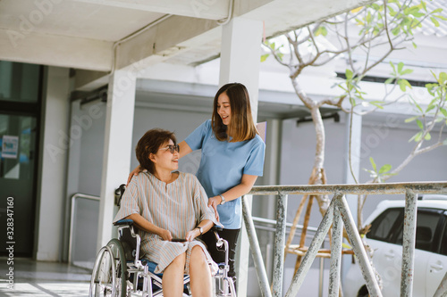Smiling physiotherapist  taking care of the happy senior patient in wheelchair