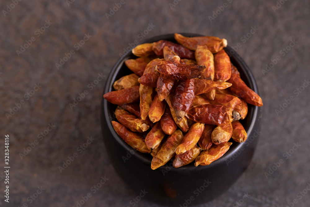 Dried chilli pepper in black bowl on concrete background. Hot and Spicy Seasoning for cooking concept. Dried chilli pepper in black bowl on concrete background. Hot and Spicy Seasoning for cooking concept.