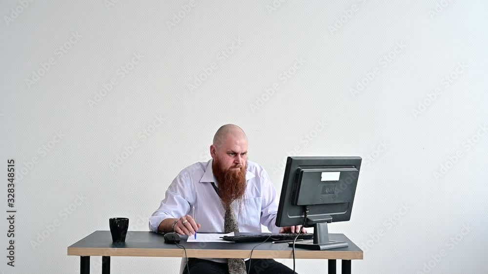 Stressed crazy businessman breaking a keyboard on his monitor in the office. The man has problems at work and frustration. The manager freaks out and breaks the computer.