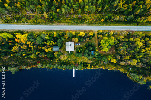 Aerial top view of log cabin or cottage with road in spring forest by the lake in Finland