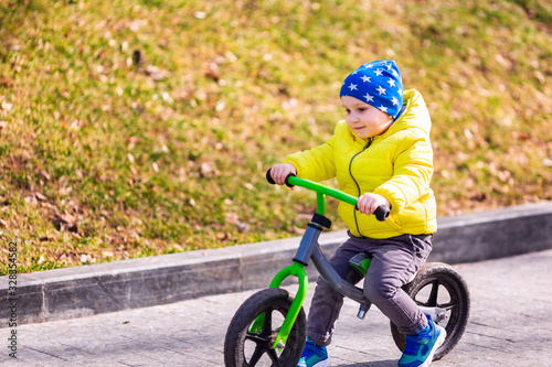 Happy little boy riding a run-bike in the park