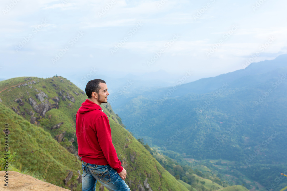 A man enjoying the mountain scenery on the edge of a cliff