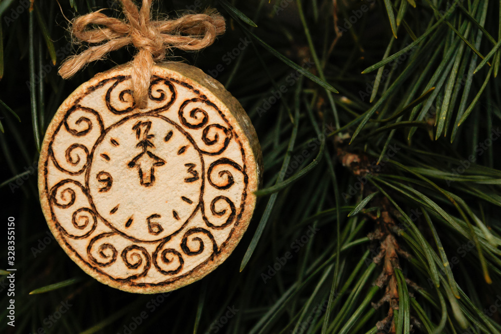 A toy on a Christmas tree made of sawn wood, a clock is burned on it.