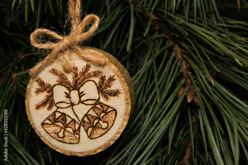 Christmas homemade toy made of sawn wood hanging on a branch, it burned bells .