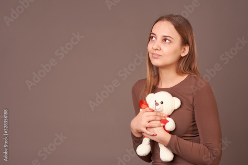 Girl with a toy bear in her hands on a gray background. Gift for birthday, Valentine's day.