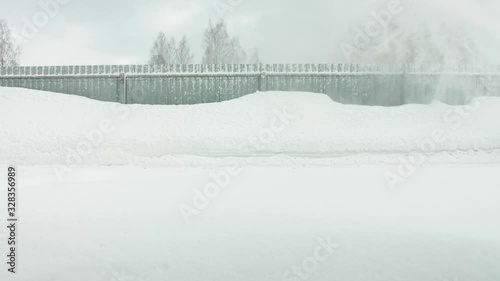 Man cleans snow with a snow thrower goes right to left static camera photo